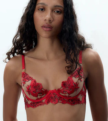 Model wearing a red lace lingerie set against a white background